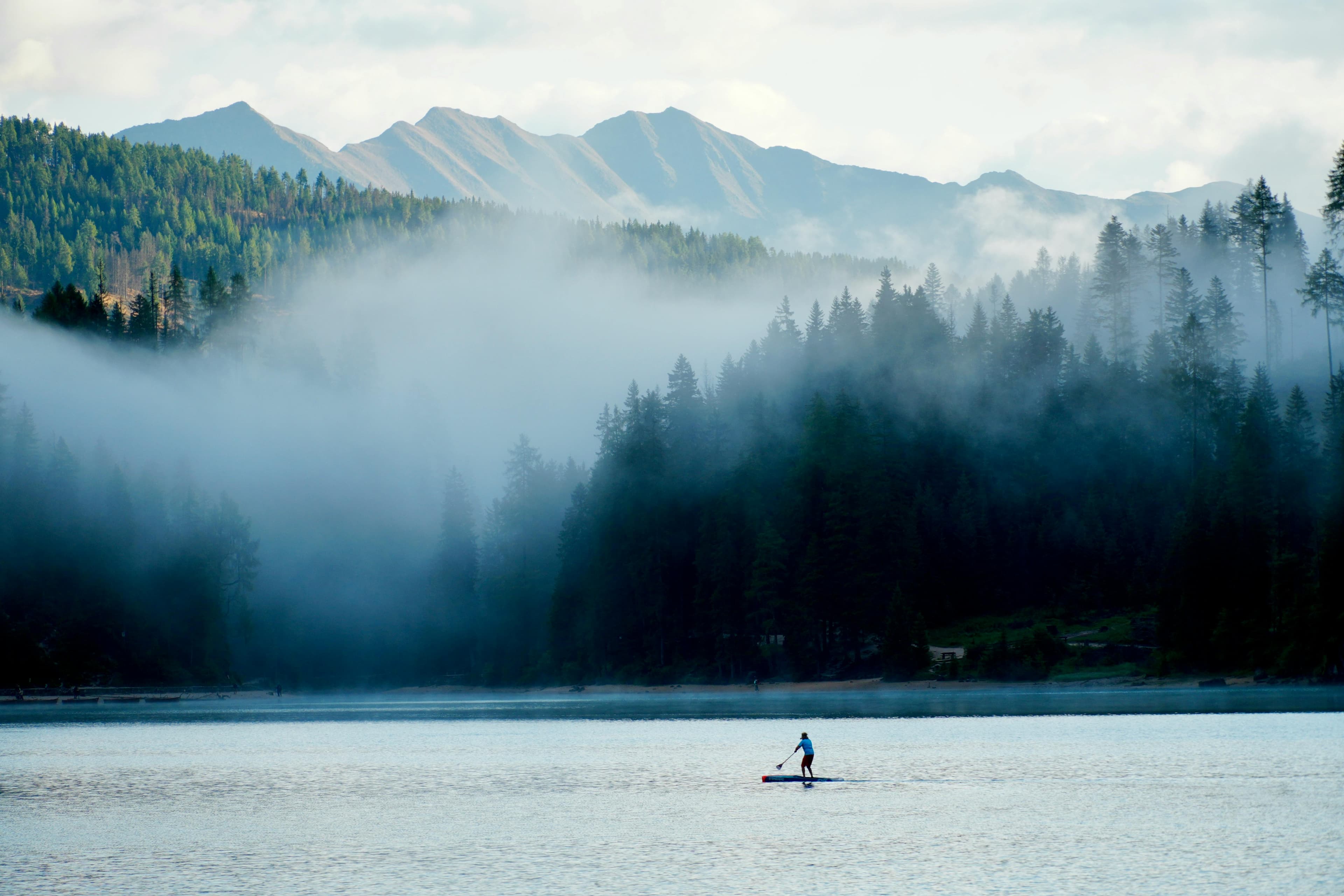 Person paddleboarding on a misty mountain lake